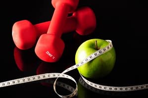 Apple, dumbells, measuring tape and weight loss