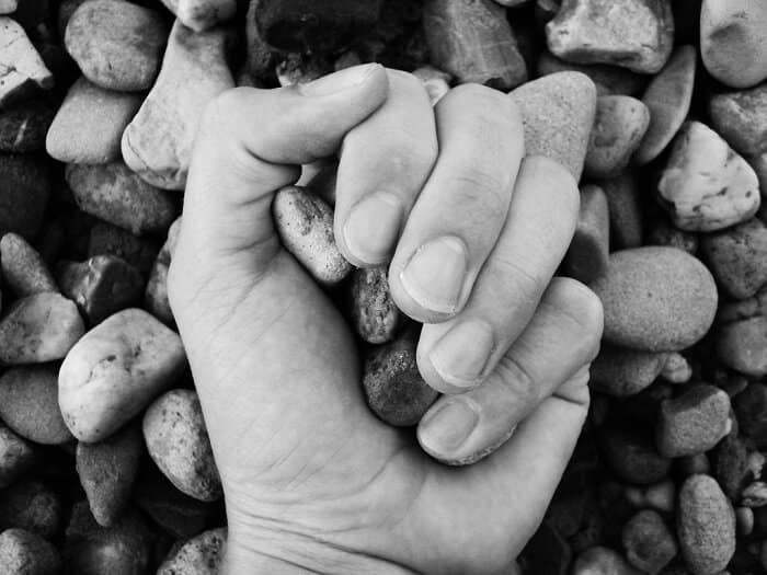 black and white of a hand holding stones with water stones in the background